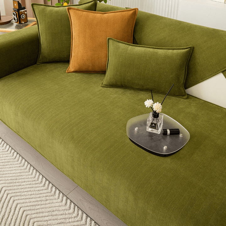 Gros plan sur le tissu vert côtelé à chevrons de la housse, avec coussins verts et moutarde et plateau en verre. 9