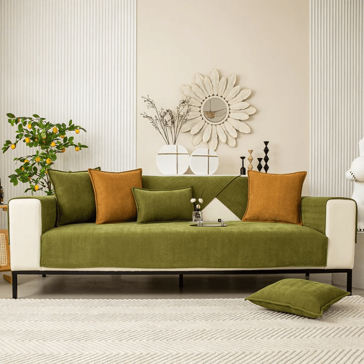 Canapé trois places entièrement habillé d'une housse verte, avec coussins verts et moutarde dans un salon clair décoré. 8