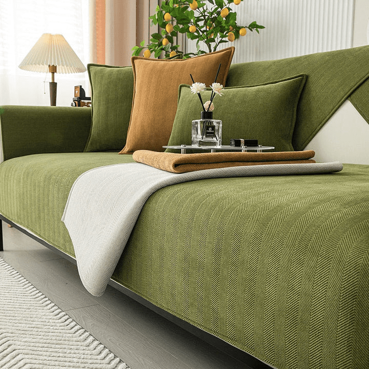Housse verte à chevrons dont un coin est rabattu pour montrer l'envers gris clair, avec plaid moutarde plié sur l'assise. 5