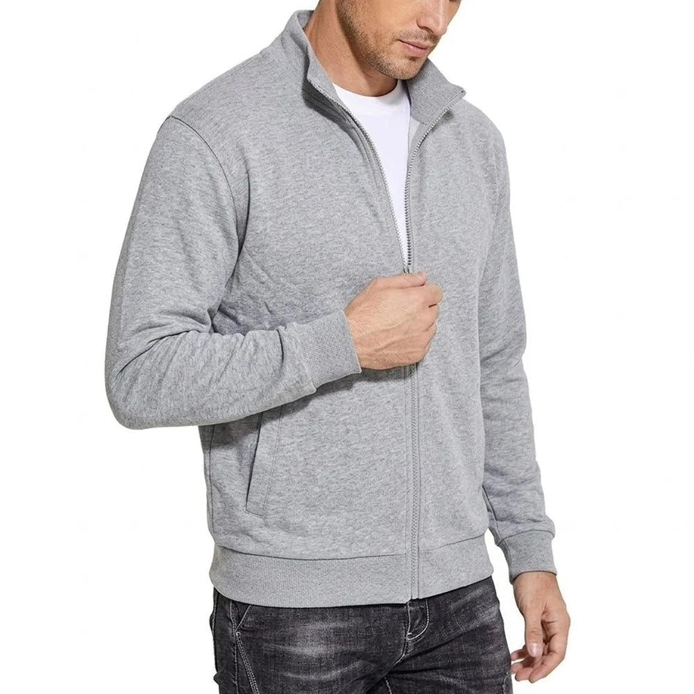 Vue de trois quarts de la veste zippée gris chiné, col montant fermé, main sur la fermeture, poches latérales visibles. 2