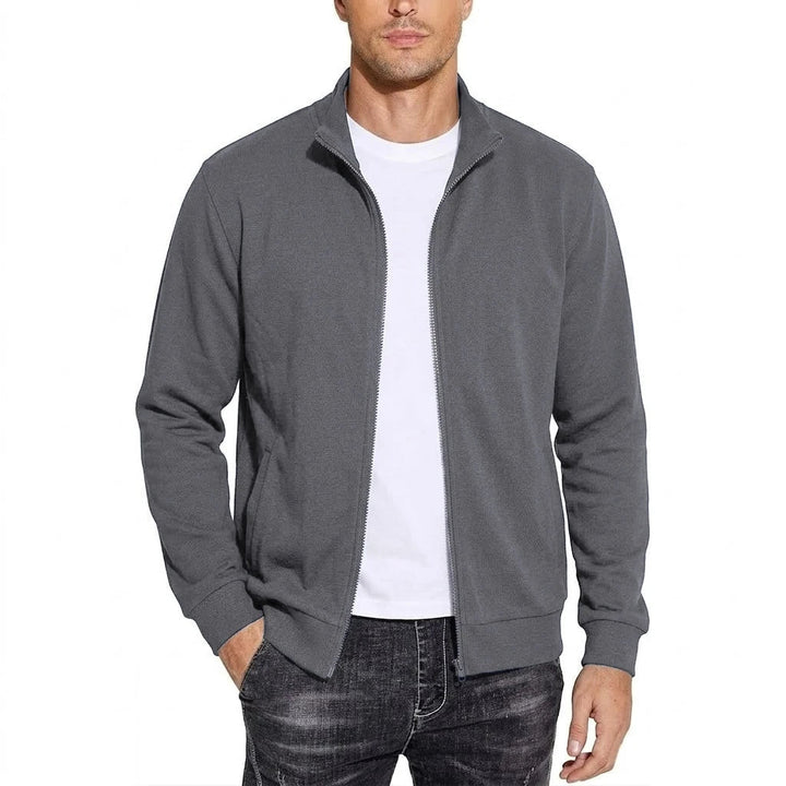 Homme portant la veste zippée gris foncé ouverte sur un t-shirt blanc, col montant, une main glissée dans la poche. 5