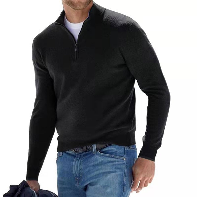 Homme portant le pull noir à col zippé sur un t-shirt blanc, avec un jean bleu et une veste à la main. 6