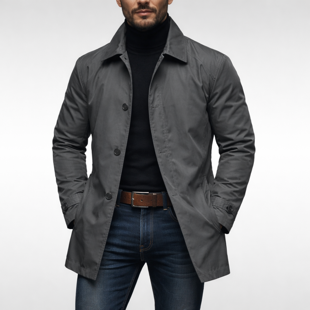 Vue de face du manteau gris foncé porté par un modèle avec col roulé noir, ceinture marron et jean. 2