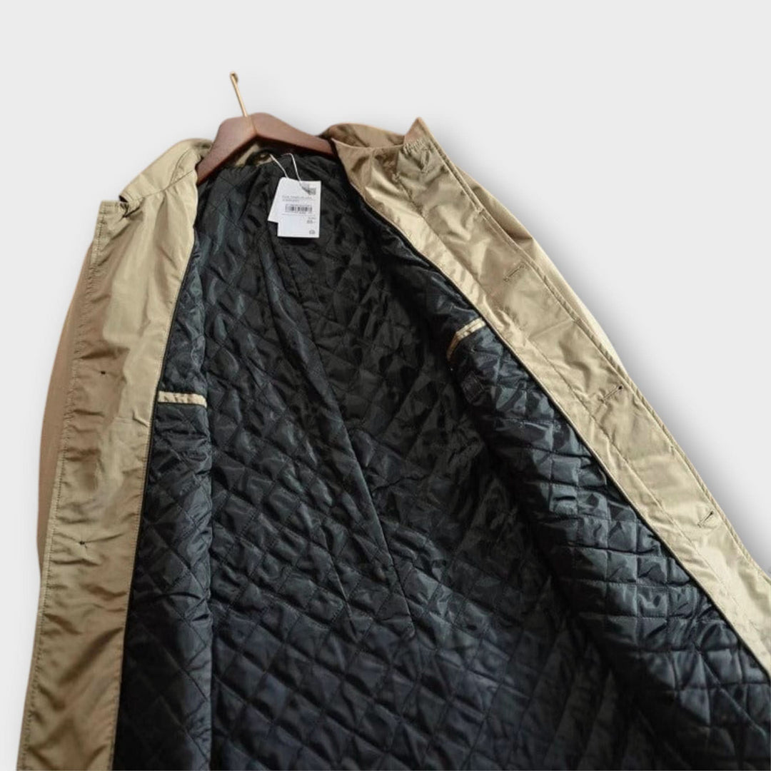 Intérieur ouvert du manteau beige accroché à un cintre, avec la doublure noire matelassée en losanges. 6