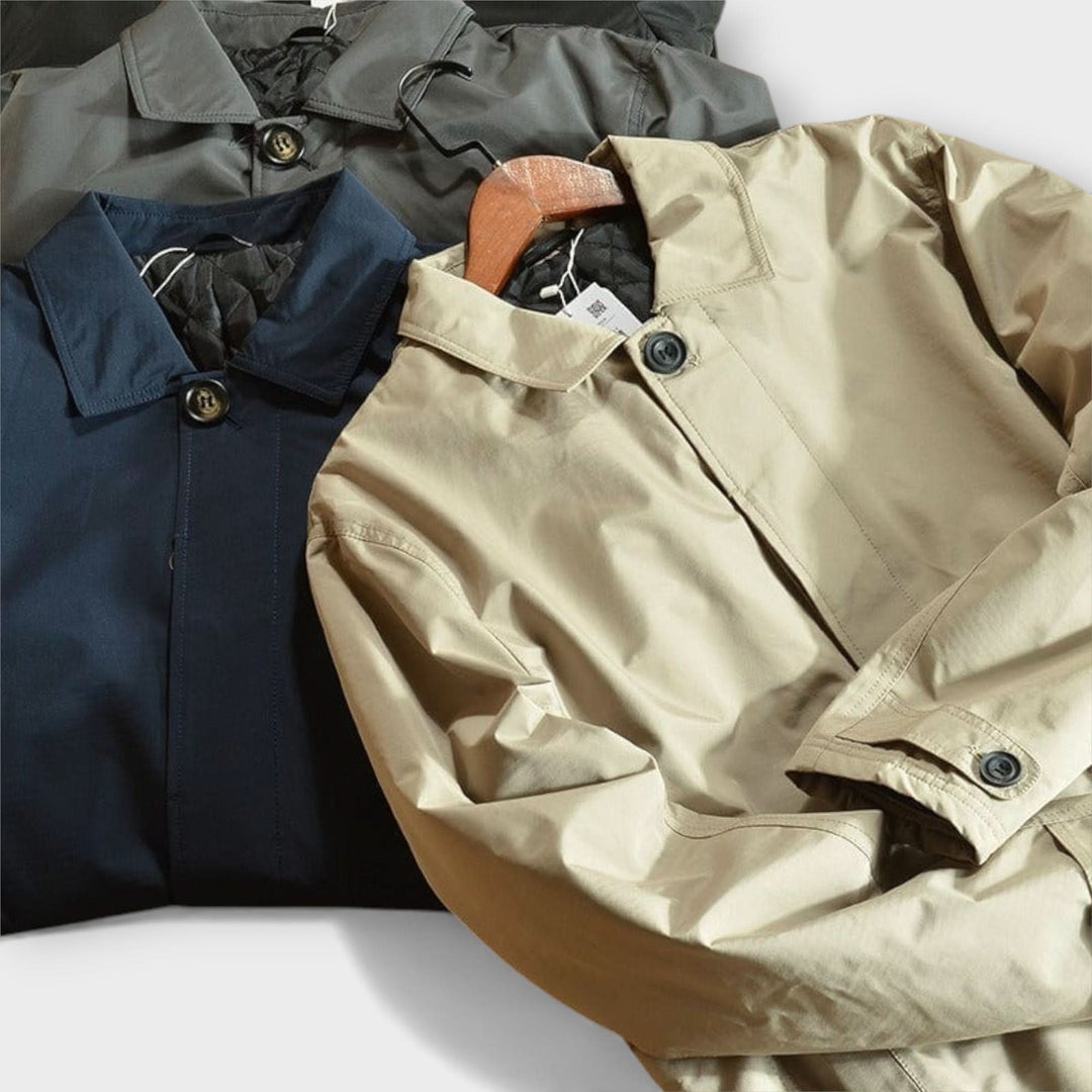 Trois manteaux posés à plat côte à côte, beige, bleu marine et gris, avec cols rabattus et boutons visibles. 9