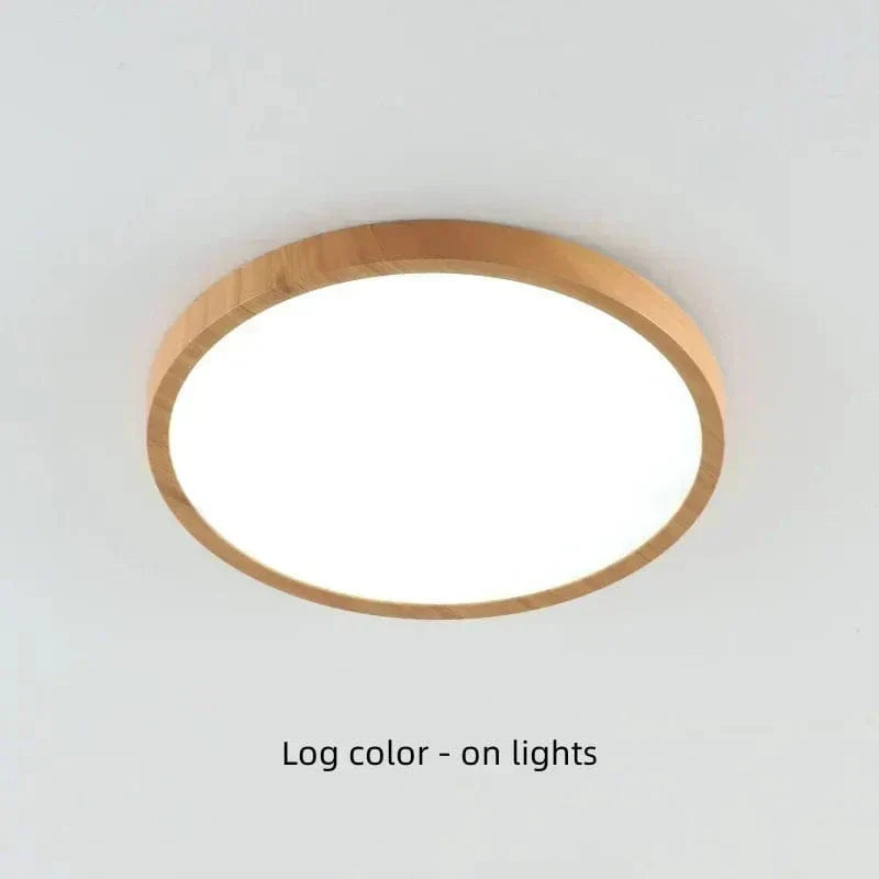 Plafonnier rond à cadre bois clair allumé, diffuseur blanc lumineux, vu en légère contre-plongée sur un plafond blanc. 20