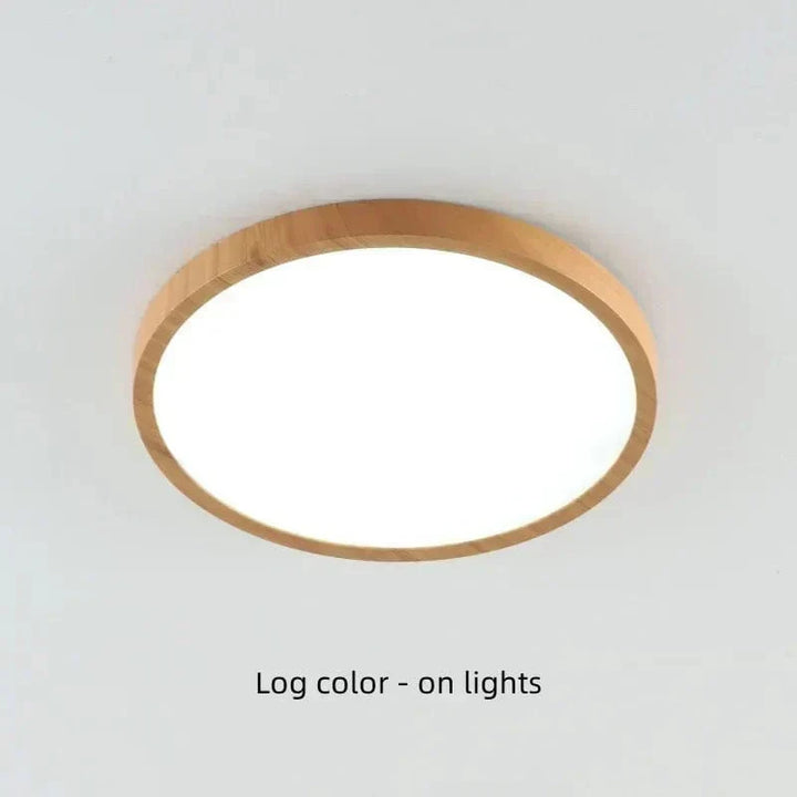 Plafonnier rond à cadre bois clair allumé, diffuseur blanc lumineux, vu en légère contre-plongée sur un plafond blanc. 20