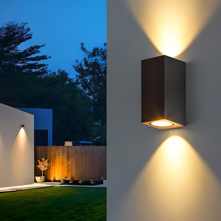 Applique rectangulaire noire à double faisceau en gros plan, avec un jardin éclairé et une clôture en bois 9