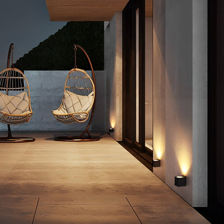 Petites appliques cubiques noires en bas de mur sur une terrasse, avec deux fauteuils suspendus en rotin 10