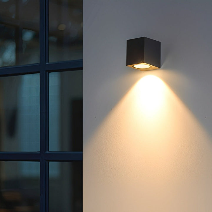 Applique cubique noire à côté d'une fenêtre à petits carreaux, projetant un cône de lumière chaude 11