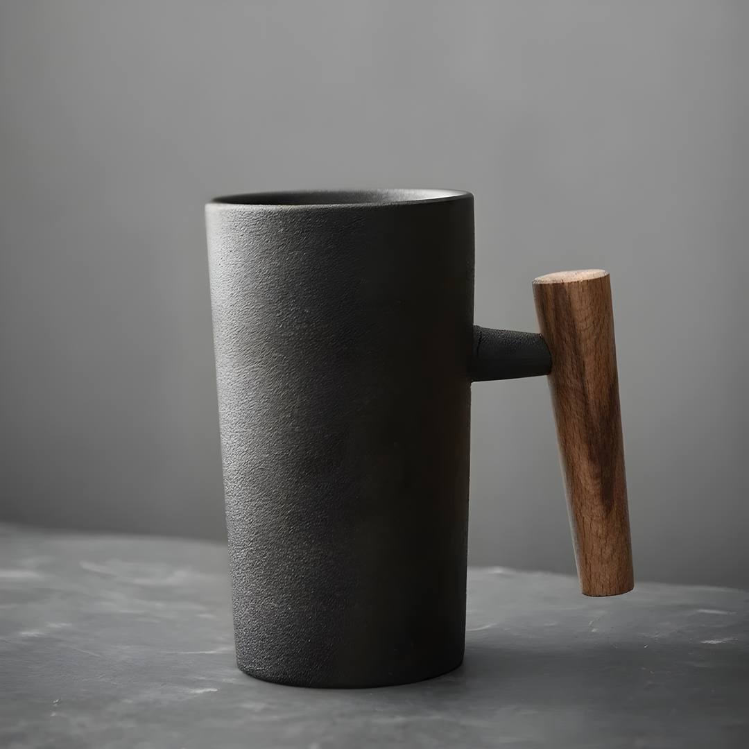 Tasse en grès noir mat texturé avec anse en bois foncé, vue de côté sur fond gris 2