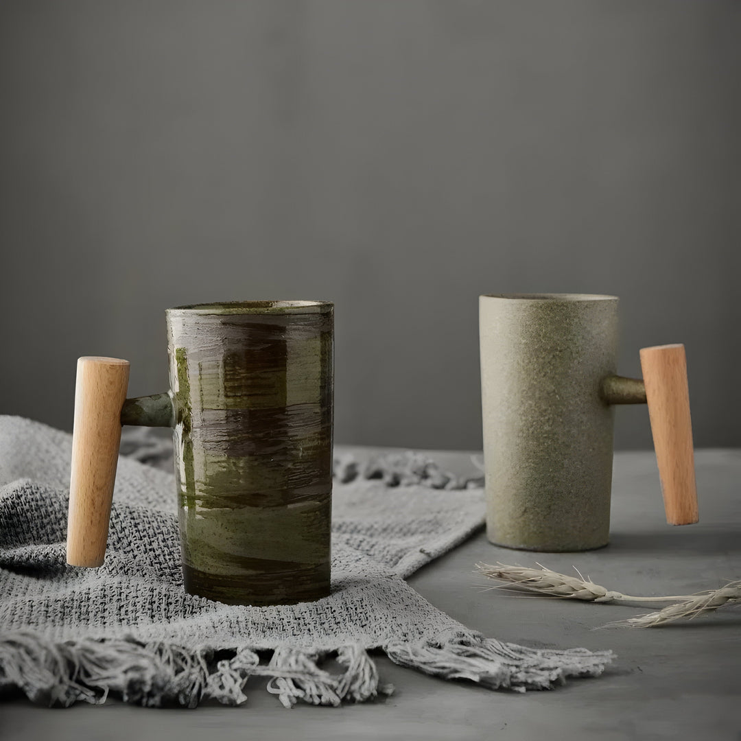 Deux tasses en grès à anse en bois, l'une vert brossé, l'autre beige, posées sur un plaid gris 1
