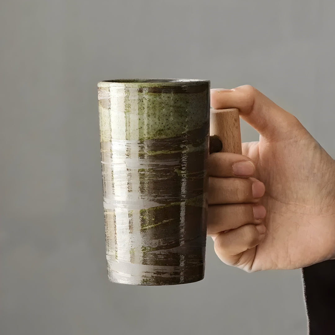 Main tenant par l'anse en bois la tasse en grès émaillé vert et brun 9