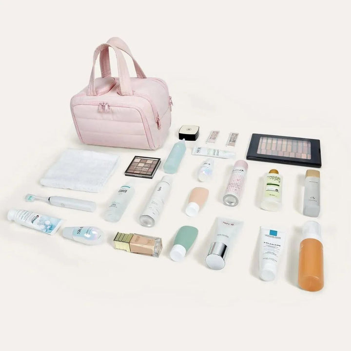 Trousse rose posée à côté de tout son contenu étalé : flacons, tubes, palette de maquillage, brosse à dents et serviette. 4