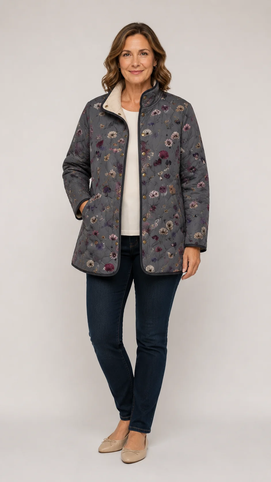 Femme portant la veste matelassée grise à fleurs, ouverte sur un haut crème, avec jean foncé et ballerines beiges. 1