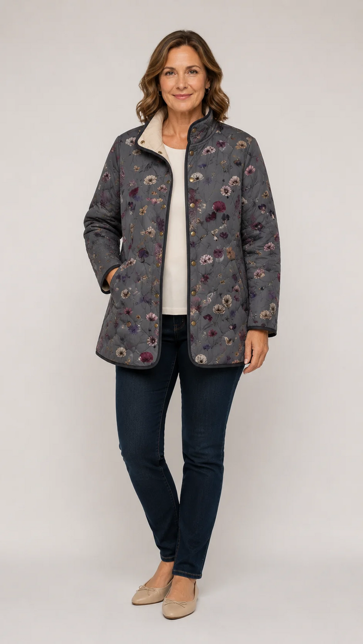 Femme portant la veste matelassée grise à fleurs, ouverte sur un haut crème, avec jean foncé et ballerines beiges. 1