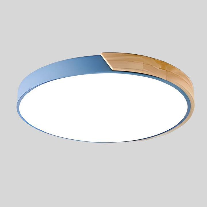 Plafonnier bleu avec segment en bois clair sur le bord, vu de dessous sur fond gris. 14