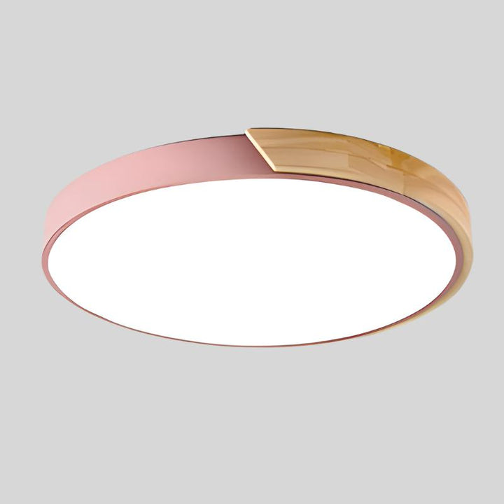 Plafonnier rose avec segment en bois clair sur le bord, vu de dessous sur fond gris. 16