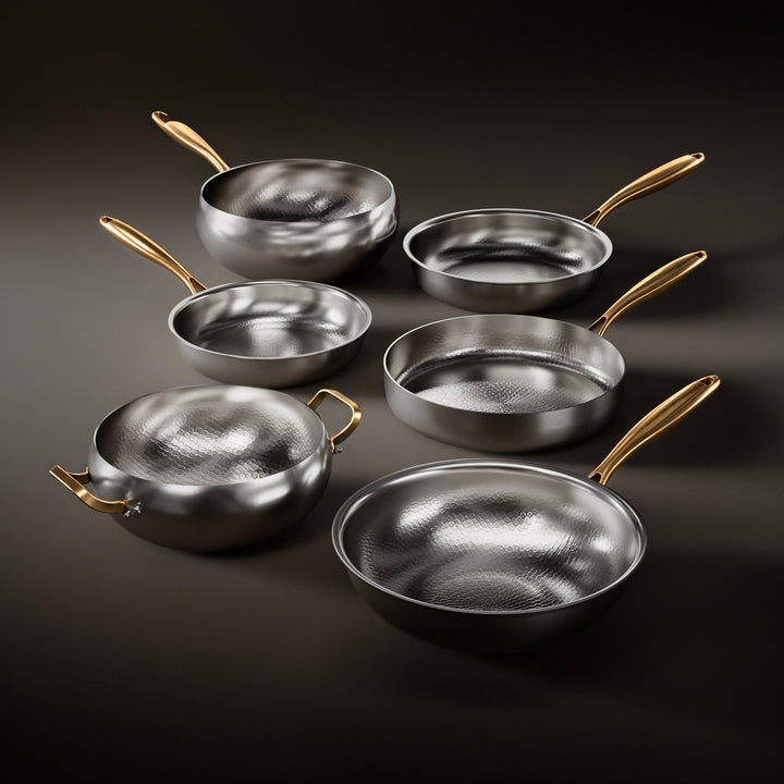Six poêles et casseroles martelées à manches dorés, dont deux woks, disposées en quinconce sur un fond sombre. 1