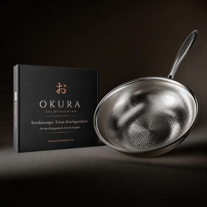 Wok martelé incliné posé à côté de son coffret noir d'emballage, sur fond sombre. 8