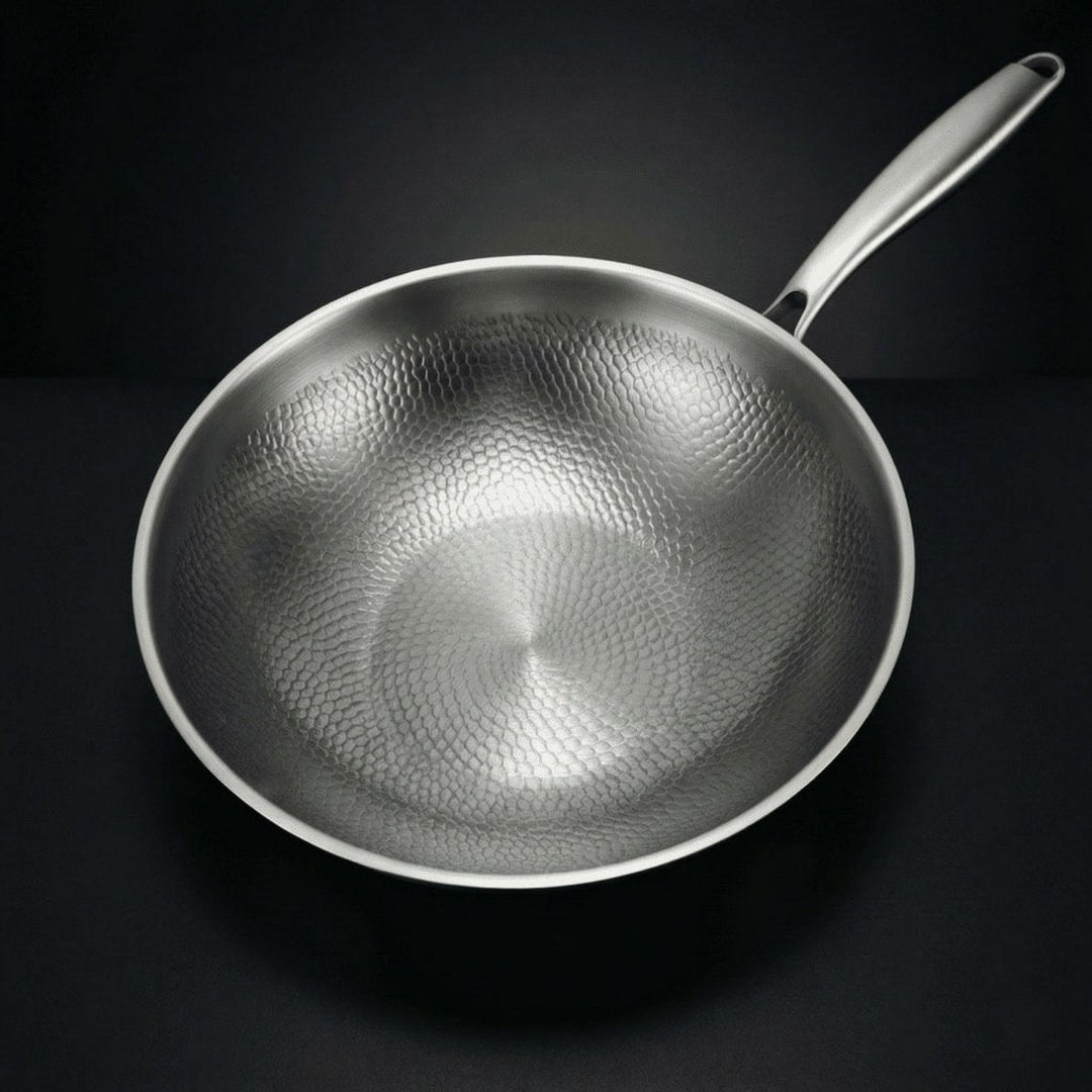 Wok vu de dessus sur fond noir, montrant le motif martelé de l'intérieur et le manche allongé. 2