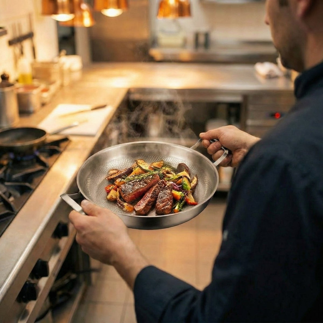 Un cuisinier tient la poêle par ses deux poignées, garnie de tranches de viande grillée et de légumes, dans une cuisine professionnelle. 6