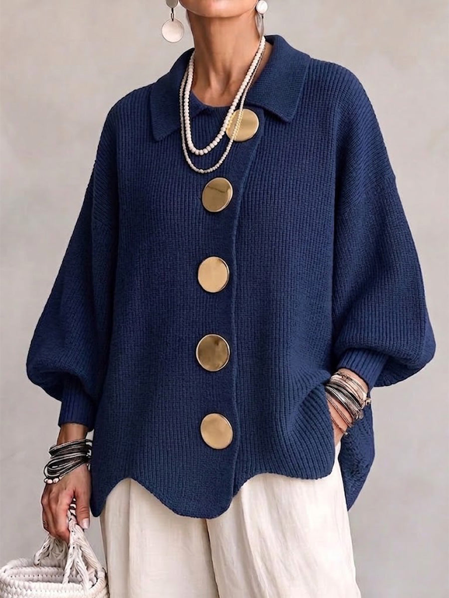 Vue de face du cardigan bleu marine en maille côtelée, porté avec un pantalon blanc, de grands boutons dorés et un col polo. 1