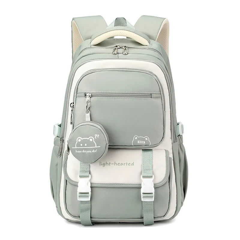 Sac à dos vert sauge et crème vu de face, avec rabat à boucles et pochette ronde assortie. 9
