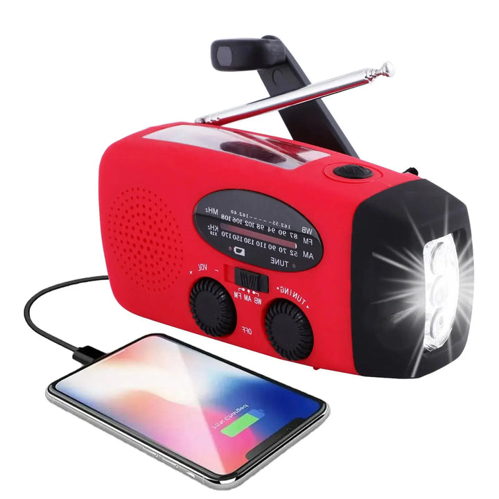Radio rouge vue de trois quarts, antenne et manivelle dépliées, lampe allumée, smartphone branché en charge 1