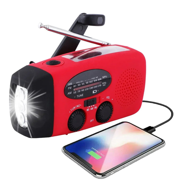 Radio rouge avec lampe LED allumée à gauche, antenne sortie, câble USB reliant un smartphone en charge 3