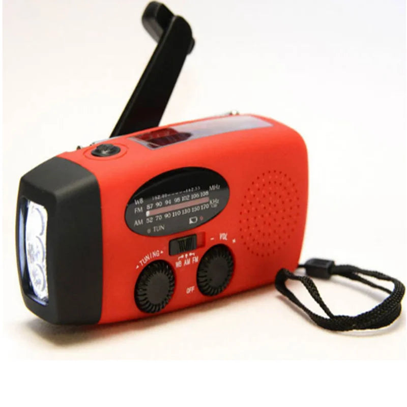 Radio rouge sur fond clair, lampe à gauche, manivelle relevée et dragonne noire à droite 2