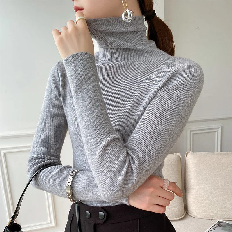 Pull gris clair à col roulé côtelé porté avec jupe noire, queue de cheval 7