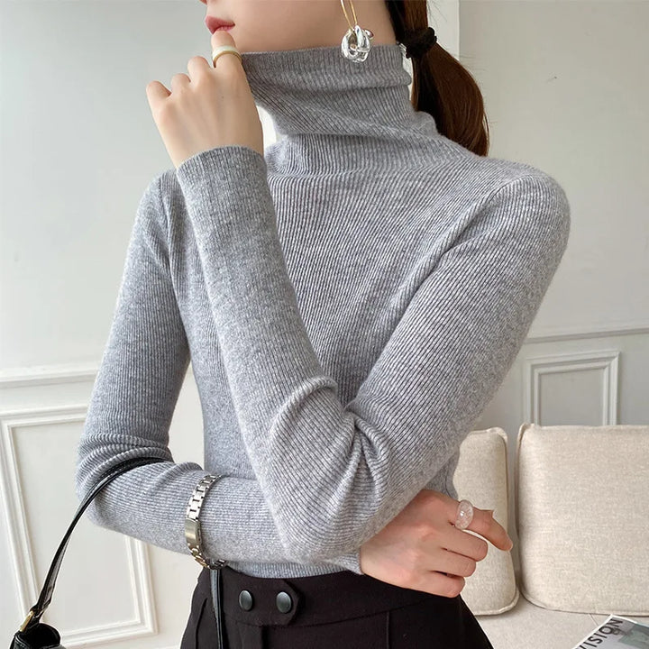 Pull gris clair à col roulé côtelé porté avec jupe noire, queue de cheval 7