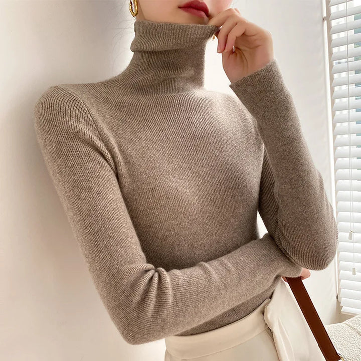 Pull taupe à col roulé côtelé porté avec pantalon crème, bras croisés 6