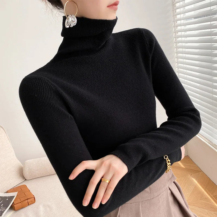 Pull noir à col roulé porté avec jupe taupe plissée, bras croisés 8