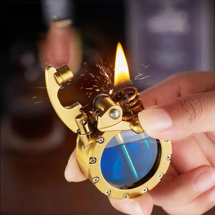 Briquet en laiton doré à réservoir bleu tenu en main, flamme allumée et étincelles jaillissant de la molette. 5