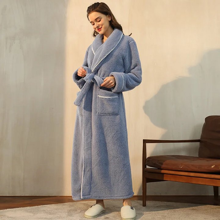 Femme souriante en peignoir bleu grisé, serrant la ceinture à la taille, assise près d'un fauteuil 4