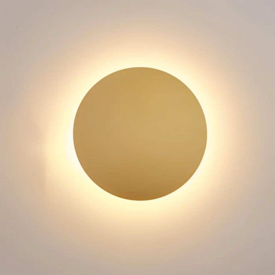 Disque doré allumé vu de face, entouré d'un halo lumineux blanc chaud sur le mur 1