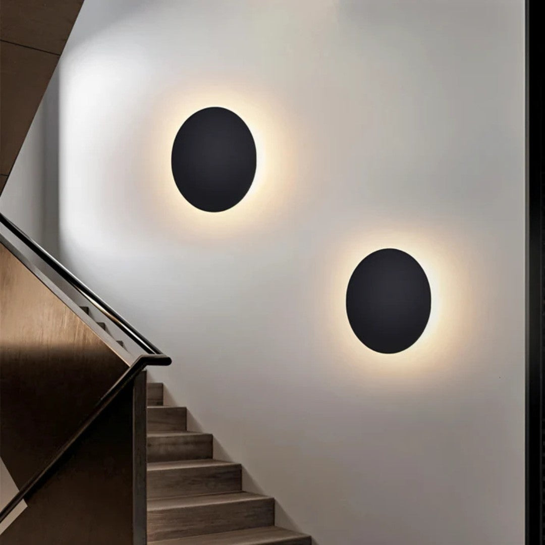 Deux appliques rondes noires fixées sur un mur blanc le long d'un escalier en bois 5