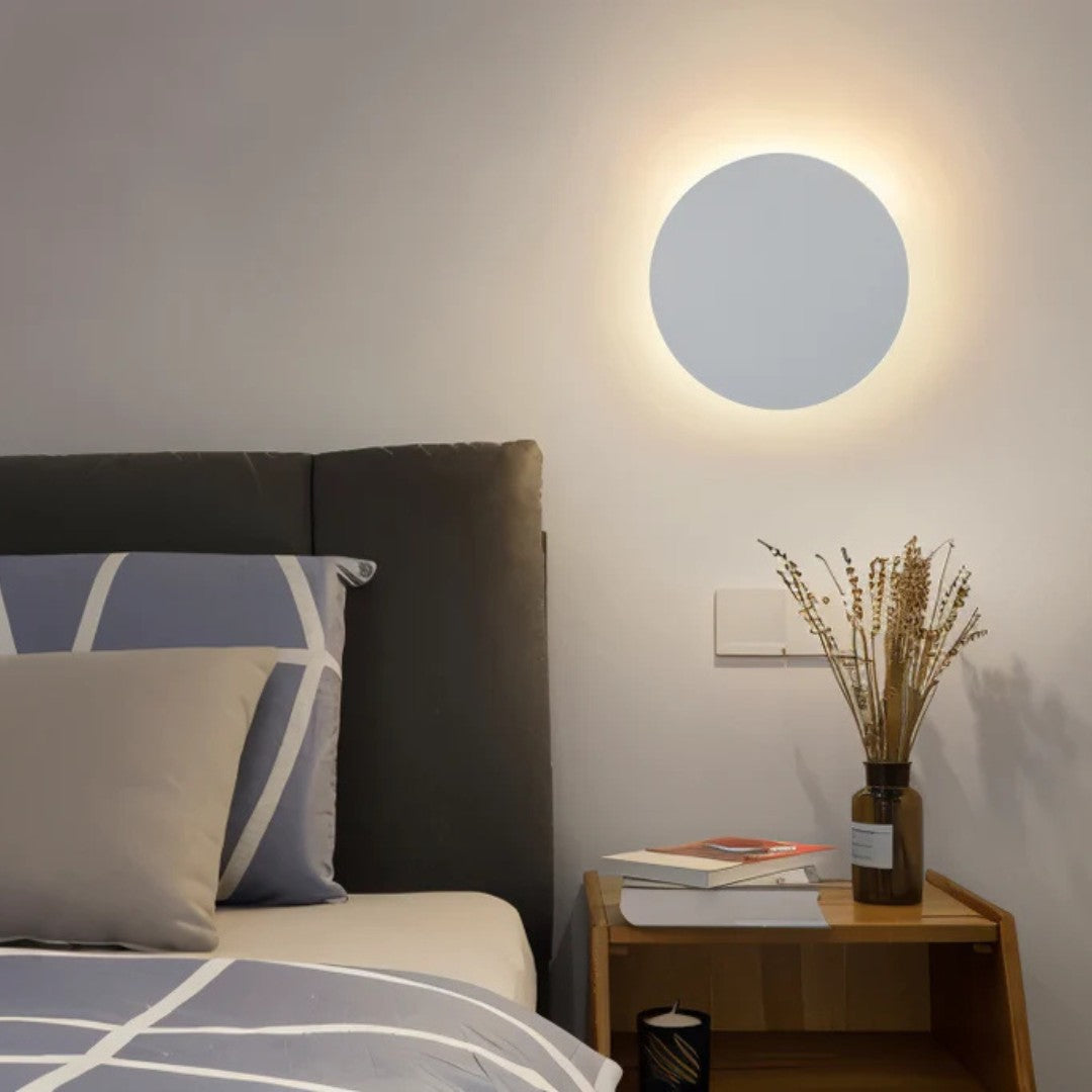 Applique ronde blanche allumée au-dessus d'une table de chevet en bois, près d'un lit gris 7