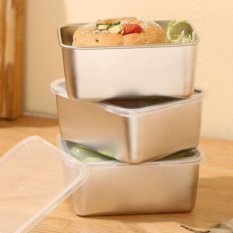 Pile de trois contenants en inox, deux avec couvercle transparent, le dessus garni d'un petit pain et de salade, un couvercle posé à côté. 10
