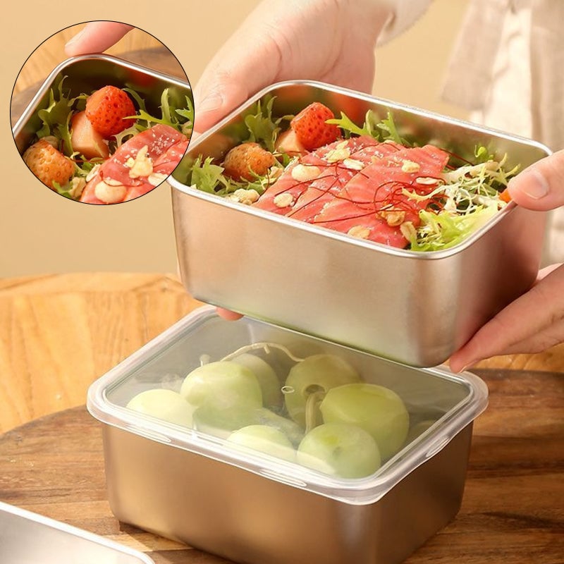 Mains tenant un contenant en inox garni de salade, saumon et fraises au-dessus d'un autre fermé par un couvercle transparent contenant des raisins. 1