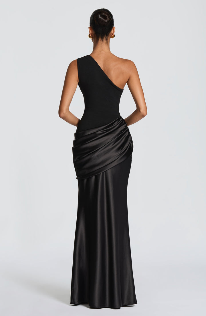 Vue de dos de la robe longue noire asymétrique portée par un mannequin, avec drapé en satin sur les hanches 21