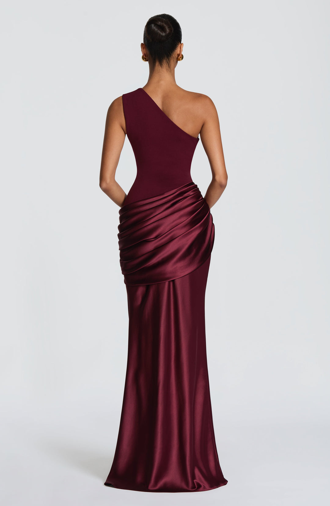 Robe longue prune devant un mur clair, mannequin un bras relevé derrière la tête, drapé satiné marqué. 18