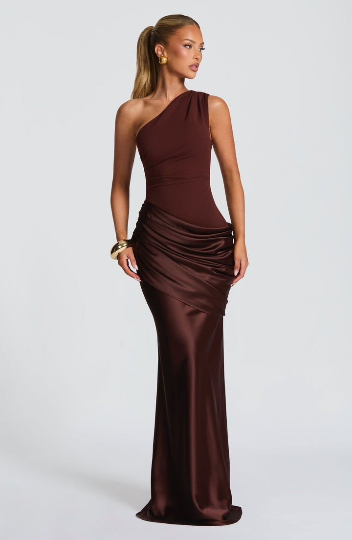 Robe asymétrique marron chocolat portée par une mannequin blonde, drapé satiné brillant sur la hanche et jupe longue. 25