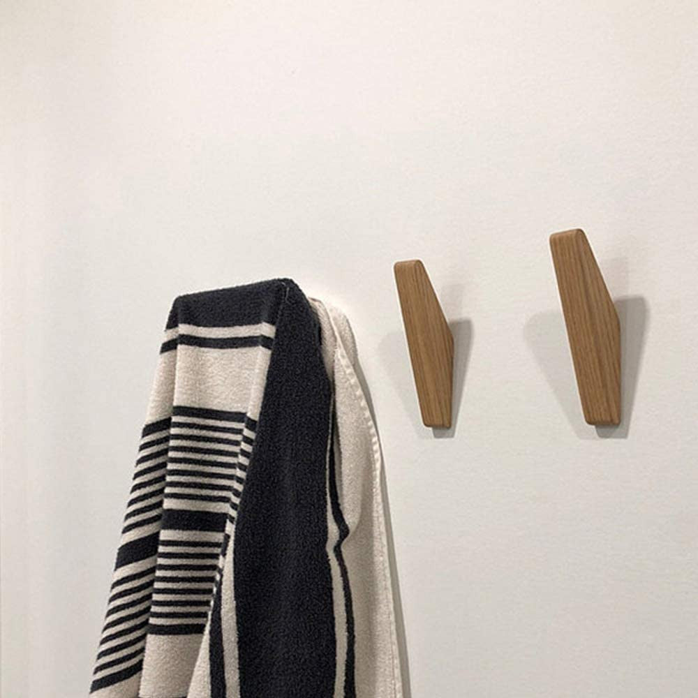 Deux crochets en bois posés sur un mur blanc, à côté d'une serviette rayée noire et blanche accrochée à un troisième. 4