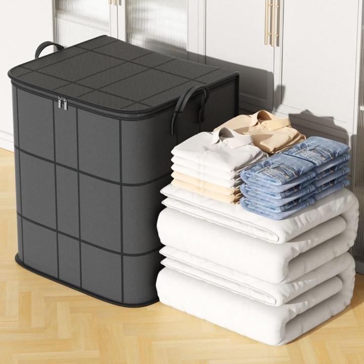 Sac gris fermé à côté de piles de couettes blanches, de chemises et de jeans pliés. 4