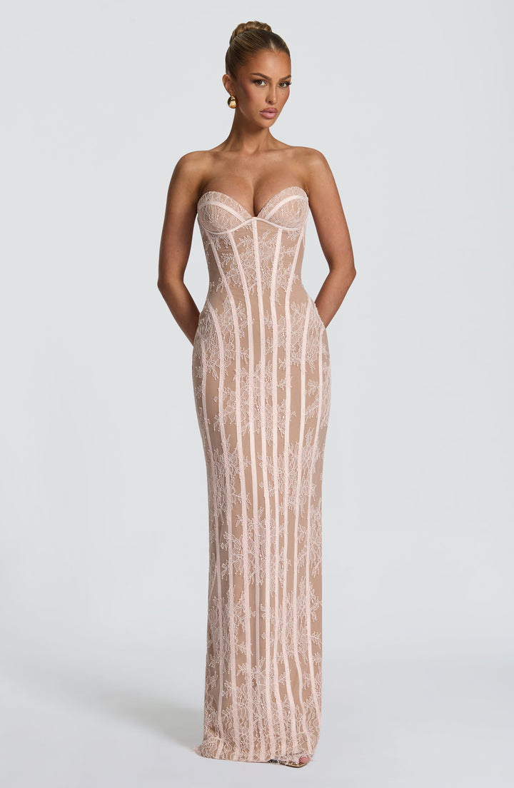 Robe longue rose pâle en dentelle florale portée de face, bras le long du corps, bustier à baleines. 13