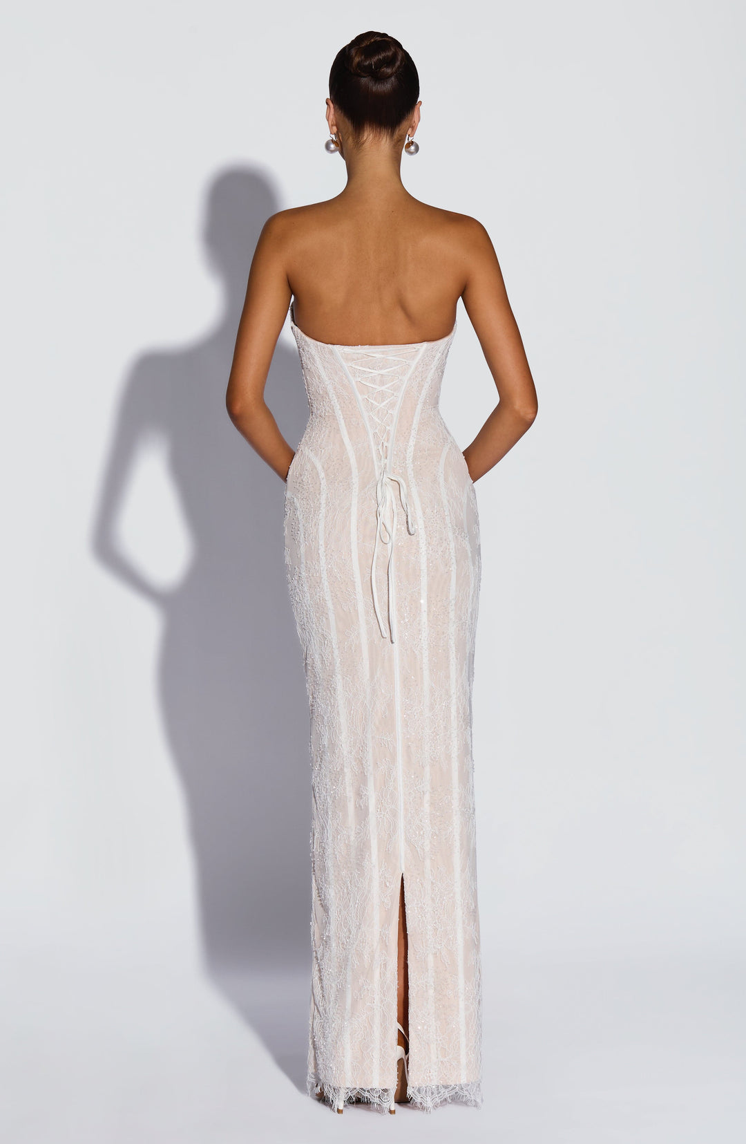 Dos de la robe blanche en dentelle avec laçage corset, rubans pendants et fente centrale au bas. 10