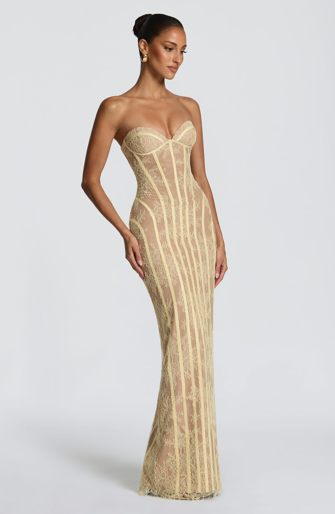 Robe jaune pâle en dentelle portée de trois quarts, mannequin le regard baissé, taille marquée par les baleines. 19